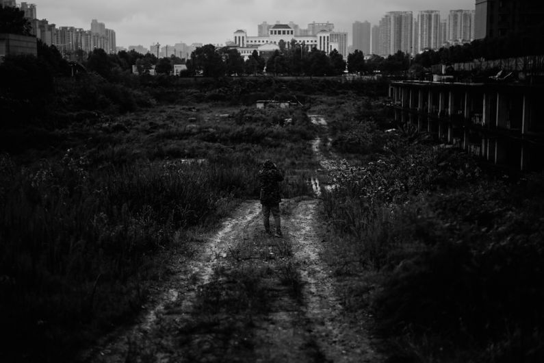 Implications - a black and white photo of a person walking down a dirt road