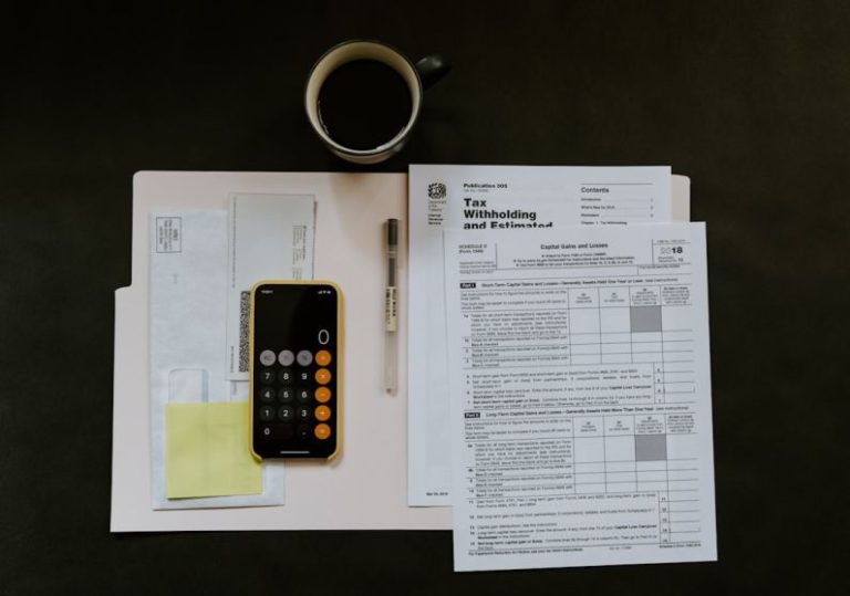 Tax - black Android smartphone near ballpoint pen, tax withholding certificate on top of white folder