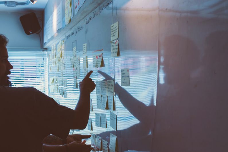 Strategies - person pointing white paper on wall