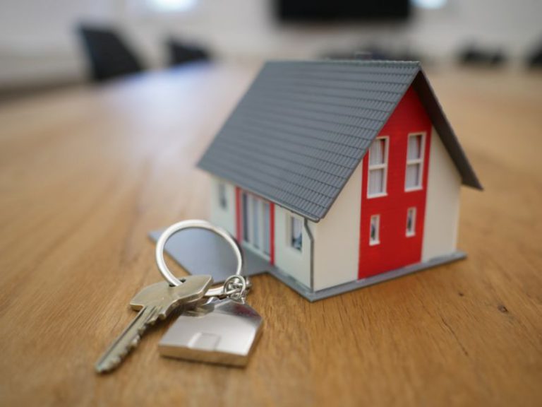 Property - white and red wooden house miniature on brown table