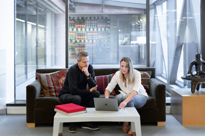 Agent - man and woman sitting on couch using macbook