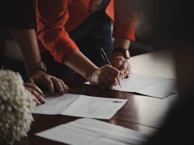 Documents - person in orange long sleeve shirt writing on white paper