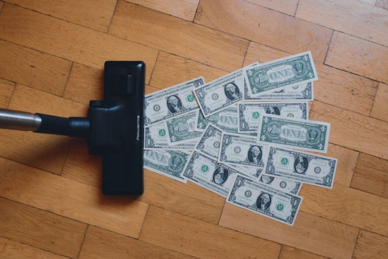 Cost - a pile of money sitting on top of a wooden floor