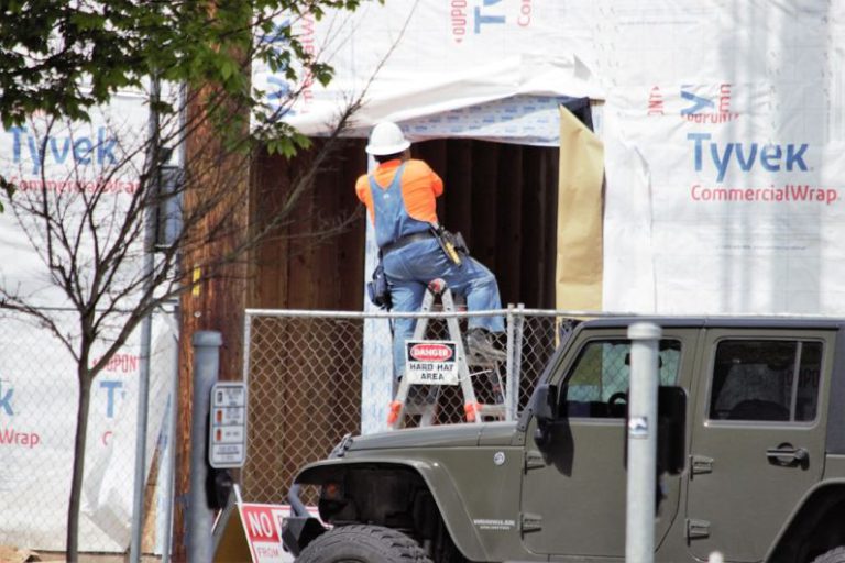Upgrades - a man on a ladder working on a jeep