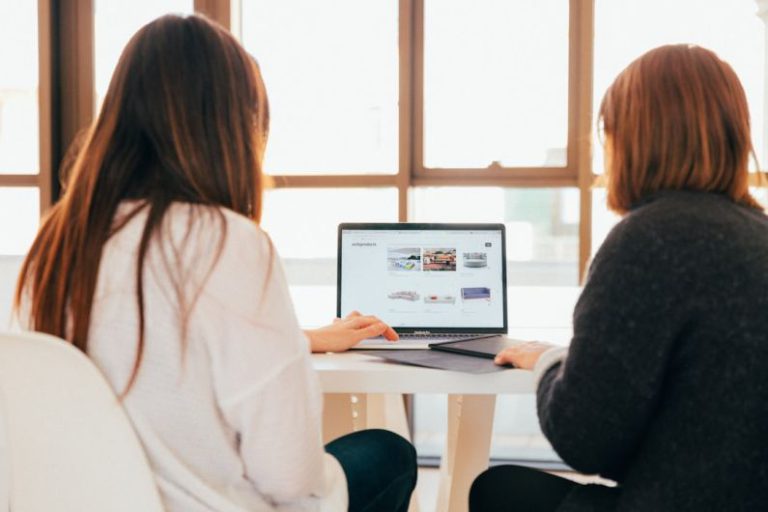 Offers - two women talking while looking at laptop computer